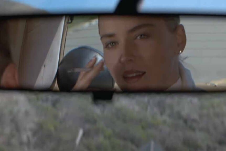 Catherine Tramell (Sharon Stone) smokes a cigarette in a car's rearview mirror  in Basic Instinct (1992).