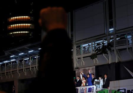 A man (front) raises his fist to show his support for Japan's Prime Minister Shinzo Abe (C top on a truck), leader of the Liberal Democratic Party, at an election campaign rally in Tokyo, Japan October 21, 2017. REUTERS/Kim Kyung-Hoon