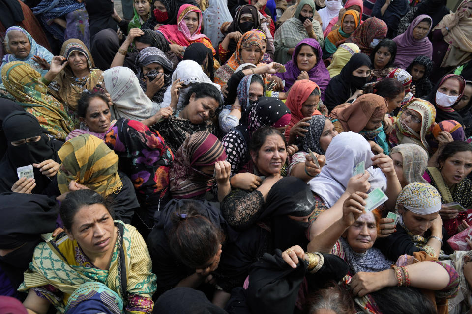 Women jostle to get a free sack of wheat flour at a distributing point, in Lahore, Pakistan, Monday, March 20, 2023. Pakistan's Prime Minister Shahbaz Sharif will provide free flour to deserving and poor families during the Muslim's holy month of Ramadan due to high inflation in the country. (AP Photo/K.M. Chaudary)