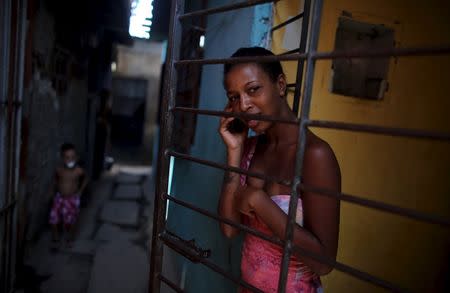 A woman talks on her mobile phone at the entrance of her stilt house, a lake dwelling also known as palafitte or 'Palafito', in Recife, Brazil, February 6, 2016. REUTERS/Nacho Doce