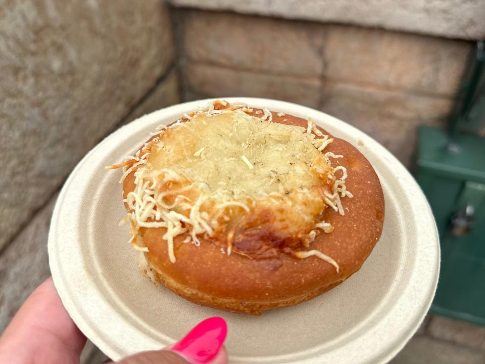 hand holding a plate with a cheese beignet from epcot's food and wine festival