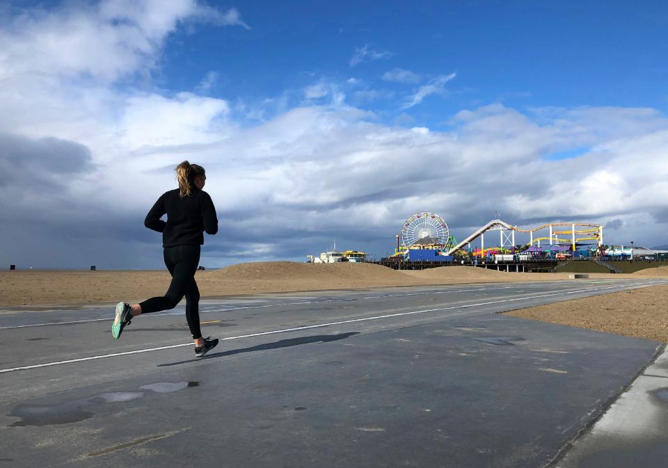 A lone runner heads up the beachfront path toward the shuttered Santa Monica Pier in Santa Monica, California, on March 17. The beach path has since been closed, though some runners are still using it.