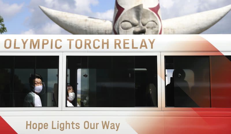 FILE PHOTO: Tokyo 2020 Olympic Torch Relay runners wearing protective masks wait inside a bus for their run at the Expo '70 Commemorative Park in Osaka