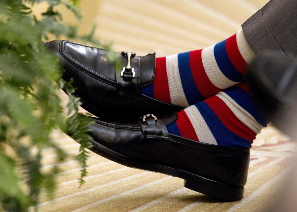 Former President George H.W. Bush crosses his red white and blue socked feet during the unveiling ceremony of former President George W. Bush, his son, and former first lady Laura Bush's portraits, Thursday, May 31, 2012, in the East Room of the White House in Washington. (AP Photo/Carolyn Kaster)