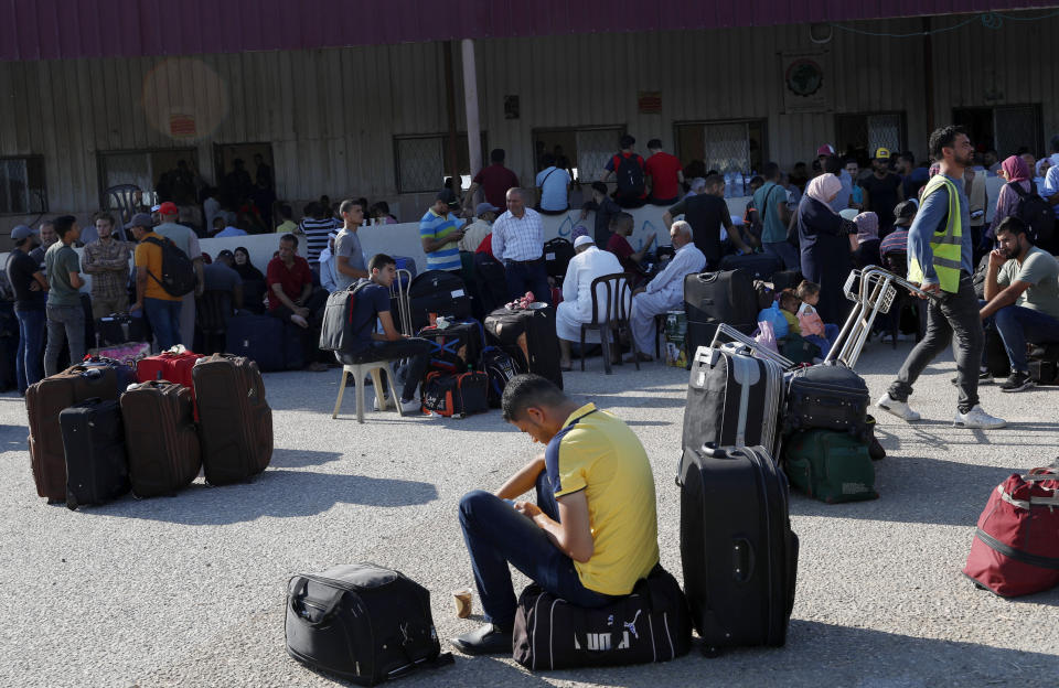 Pasajeros están sentados junto a su equipaje mientras esperan cruzar la frontera al lado egipcio del cruce Rafá, en la Franja de Gaza, el martes 11 de agosto de 2020. (AP Foto/Adel Hana)