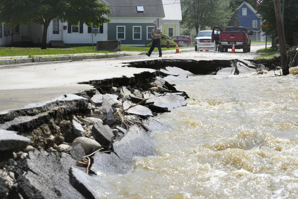 FILE - A passerby walks near a street damaged by flood waters, July 11, 2023, in Ludlow, Vt. Across the U.S., municipal water systems and sewage treatment plants are at increasing risk of damage from floods and sea-level rise brought on in part or even wholly by climate change. The storm that walloped Ludlow especially hard, damaging the picturesque ski town’s system for cleaning up sewage before it’s discharged into the Williams River. (AP Photo/Steven Senne, File)