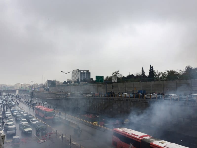 Riot police tries to disperse people as they protest on a highway against increased gas price in Tehran
