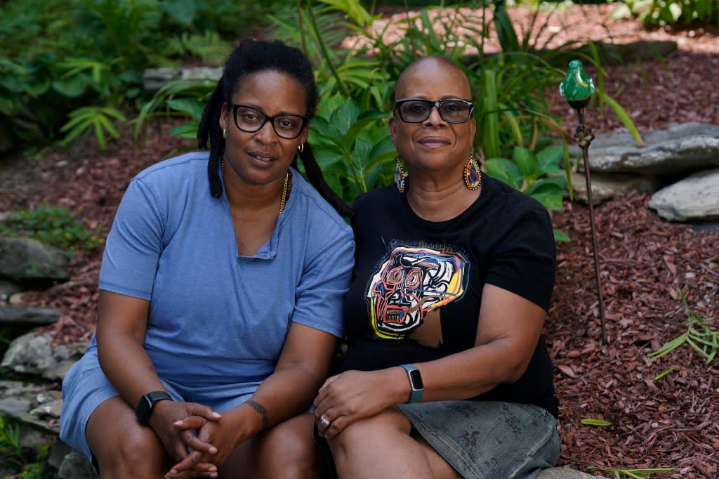 Angelique Webster, of Worcester, Mass., left, an independent filmmaker, and her mother Gloria Webster, right, who is retired and lives in Raleigh, N.C., pose, Thursday, Sept. 7, 2023, in a garden behind Angelique’s home, in Worcester. (AP Photo/Steven Senne)