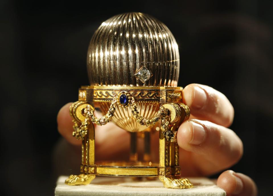 An assistant poses for a photograph with a Faberge egg during a photo-call at antique dealer Wartski, in central London