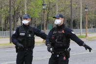 Police officers wearing protective masks wave a car into a control point at the Champs Elysees avenue in Paris, Tuesday, March 17, 2020. France is imposing nationwide restrictions on how far from their homes people can go and for what purpose as part of the country's strategy to stop the spread of the new coronavirus. For most people, the new coronavirus causes only mild or moderate symptoms, such as fever and cough. For some, especially older adults and people with existing health problems, it can cause more severe illness, including pneumonia. (AP Photo/Michel Euler)