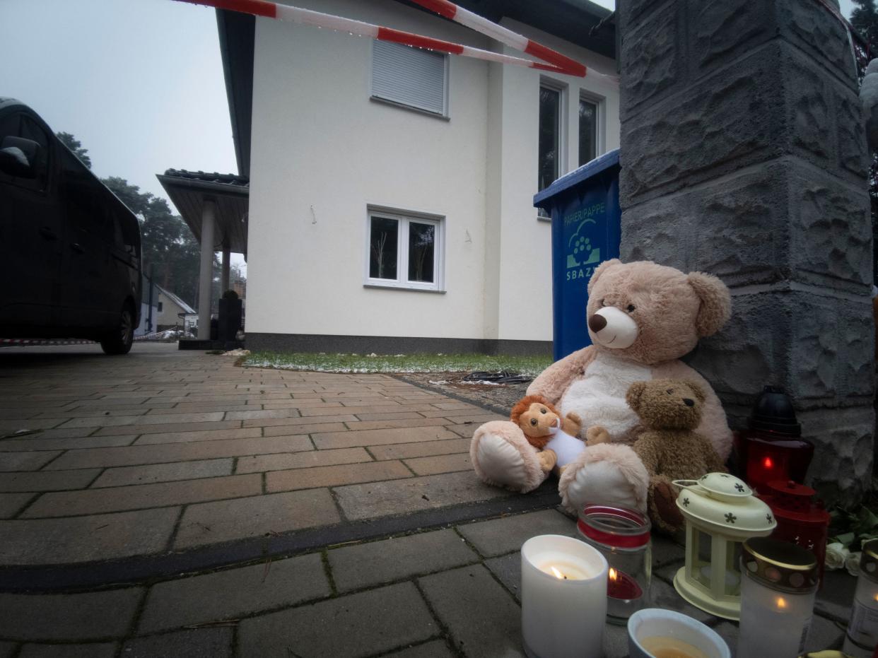 A teddy bear and candles are placed in front of a house where the lifeless bodies of two adults and three children with gunshot and stab wounds were discovered in Senzig near Koenigs-Wusterhausen, a Berlin suburb, on December 5.