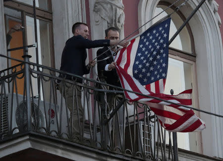 FILE PHOTO: Employees take down the U.S. flag on the U.S. Consulate General in St. Petersburg, Russia March 31, 2018. REUTERS/Anton Vaganov/File Photo