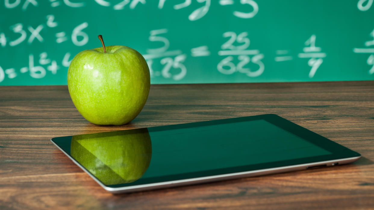  Apple iPad on desk with apple and blackboard behind showing math equations 