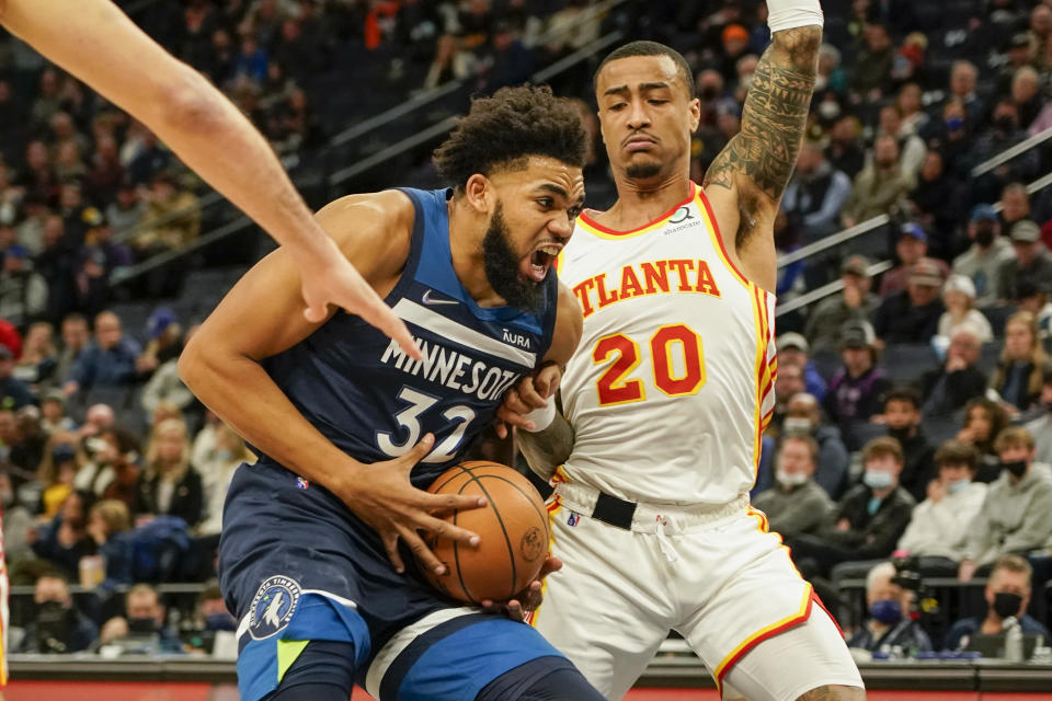 Minnesota Timberwolves center Karl-Anthony Towns, left, drives to the basket past Atlanta Hawks forward John Collins during the first half of an NBA basketball game Monday, Dec. 6, 2021, in Minneapolis. (AP Photo/Craig Lassig)