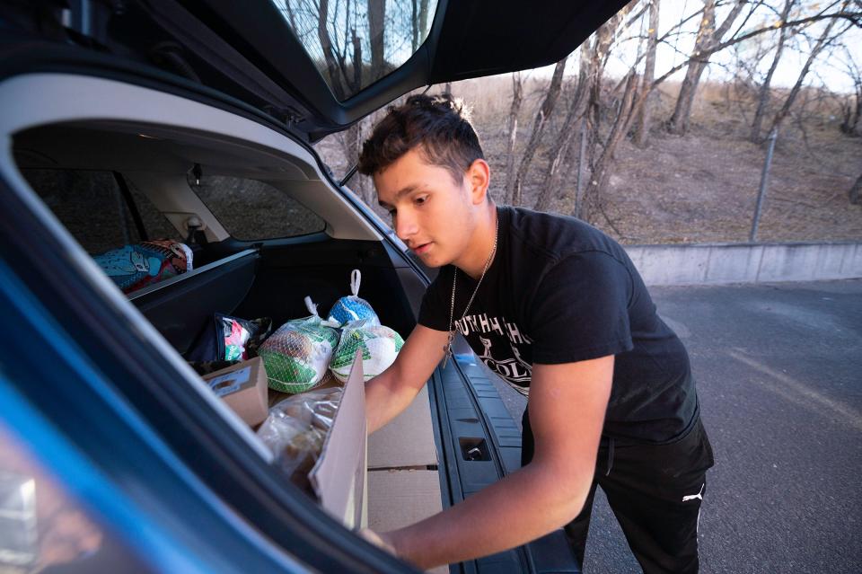 Pueblo South's Julian Hermosillo loads a box of food into the back of a vehicle during the Tom and Louie's Cupboard food drive at St. Joseph's Hall on Saturday, November 18, 2023.