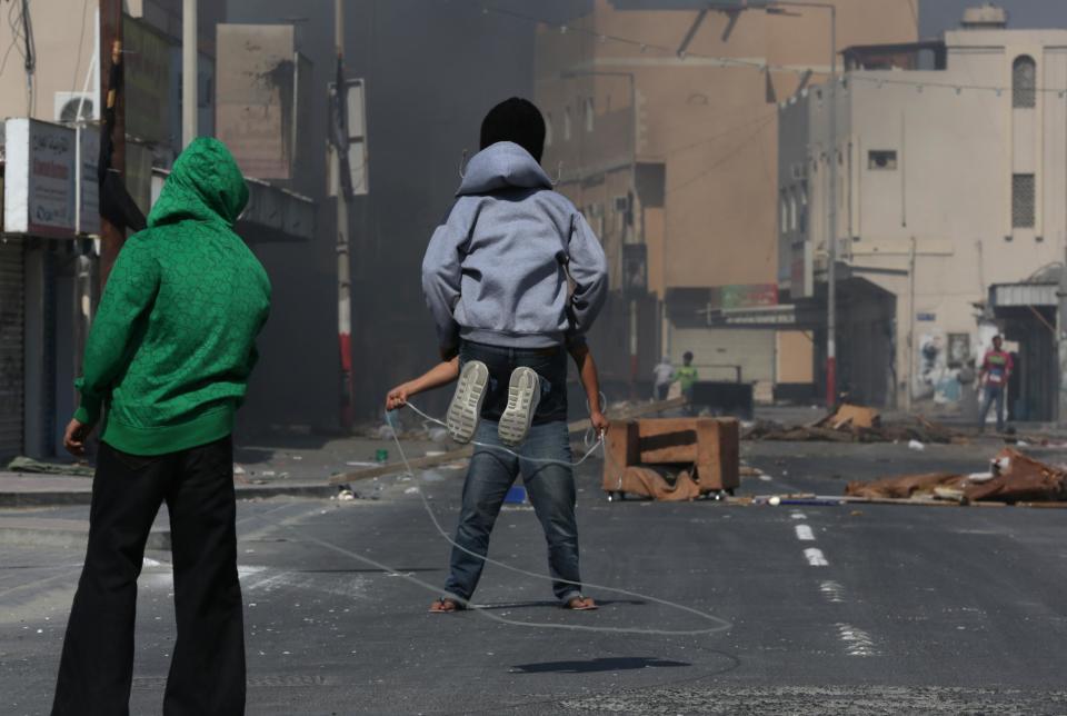 Bahraini youths jump rope as they wait for riot police between clashes on the main street of Malkiya, Bahrain, Thursday, Feb. 13, 2014. Anti-government protesters burned rubbish and smeared oil on the road to deter police jeeps from entering the village, where shops were shuttered in observance of a general strike called by anti-government groups in the run-up to Friday's third anniversary of the pro-democracy uprising in the Gulf island kingdom. (AP Photo/Hasan Jamali)