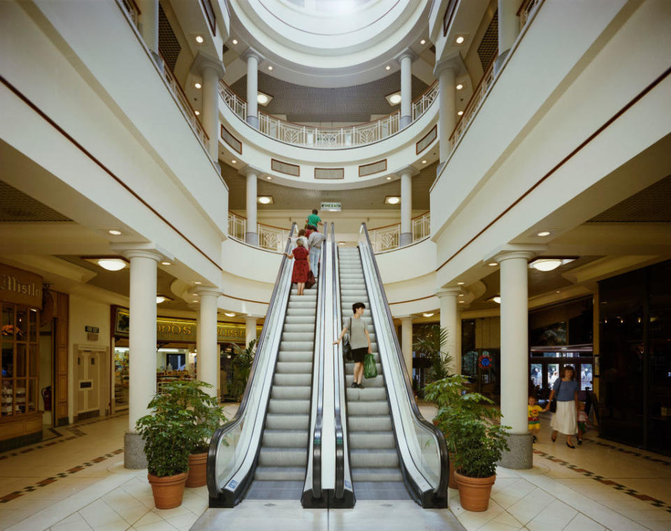 people riding escalators in a mall in the 80s