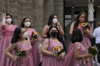 Women wearing face masks wait for the groom and bride during a wedding ceremony outside Manila's Cathedral, Philippines on Thursday, Dec. 2, 2021. Religious activities, including weddings, have resumed with greater capacity as the government continues to ease health restrictions due to the decline of COVID-19 cases in the country while closely monitoring the new omicron virus variant. (AP Photo/Aaron Favila)