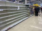 Shoppers walk past empty shelves inside a Tesco supermarket in Liverpool