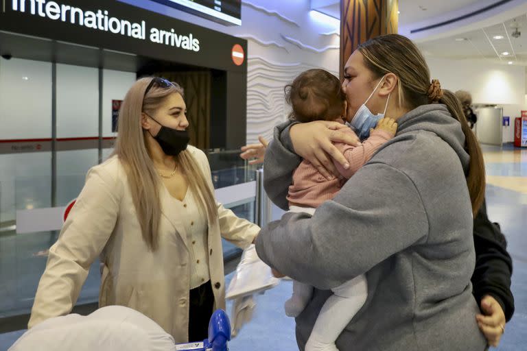 Unas familias se abrazan después de que un vuelo procedente de Los Ángeles llegara al aeropuerto internacional de Auckland al abrirse la frontera neozelandesa para los países con exención de visado el lunes 2 de mayo de 2022.