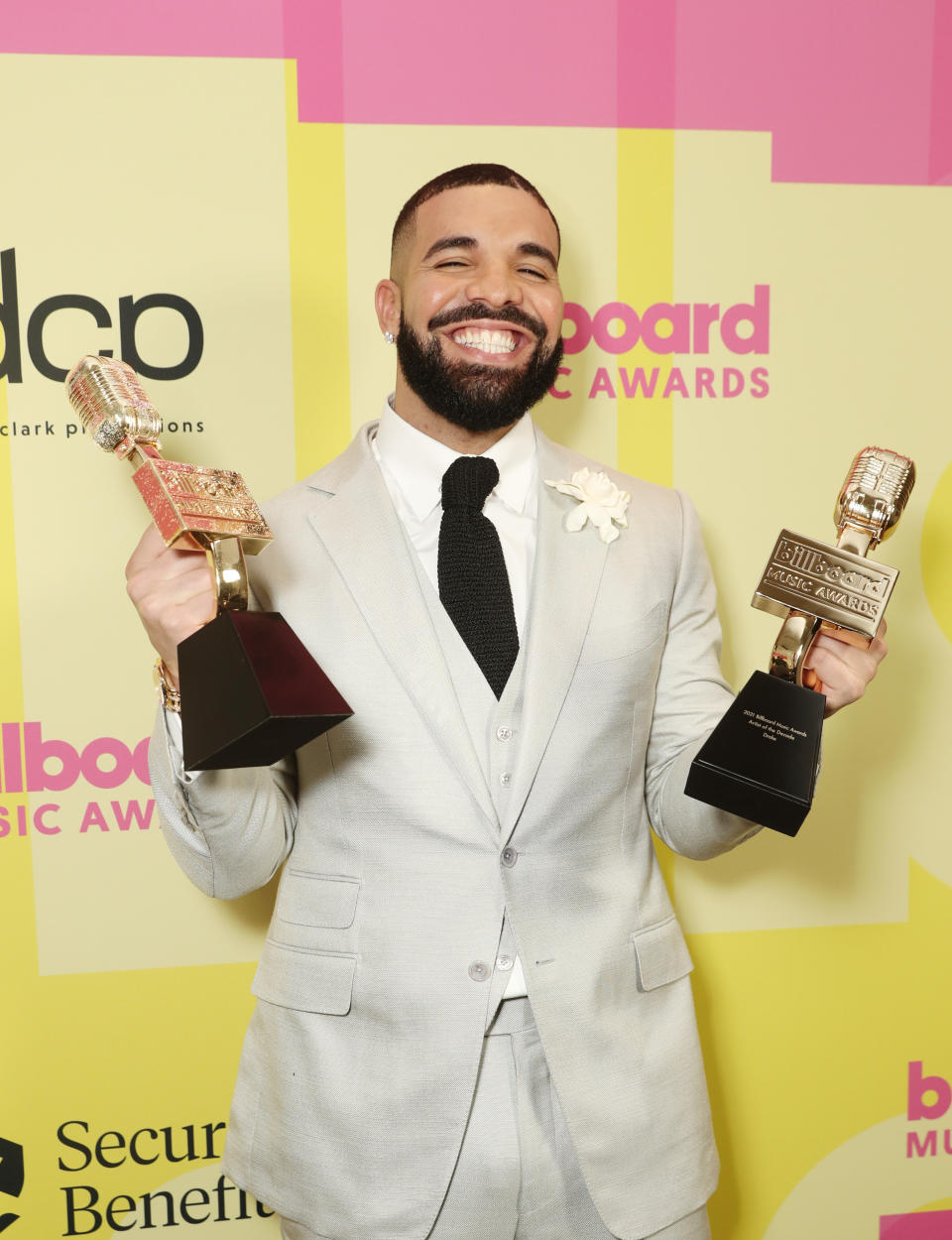 Drake smiling on the red carpet, holding up two Billboard Music Awards