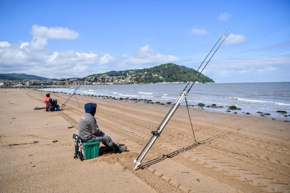 Two fishermen angle their rods towards the sea on the beach at Minehead after the announcement of plans to bring the country out of lockdown. (Photo by Ben Birchall/PA Images via Getty Images)