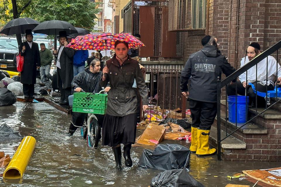 Pedestrians walk along a flooded sidewalk, Friday, Sept. 29, 2023, in the Brooklyn borough of New York. A potent rush-hour rainstorm has swamped the New York metropolitan area.