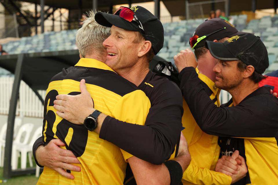 Andrew Tye and coach Adam Voges embrace.