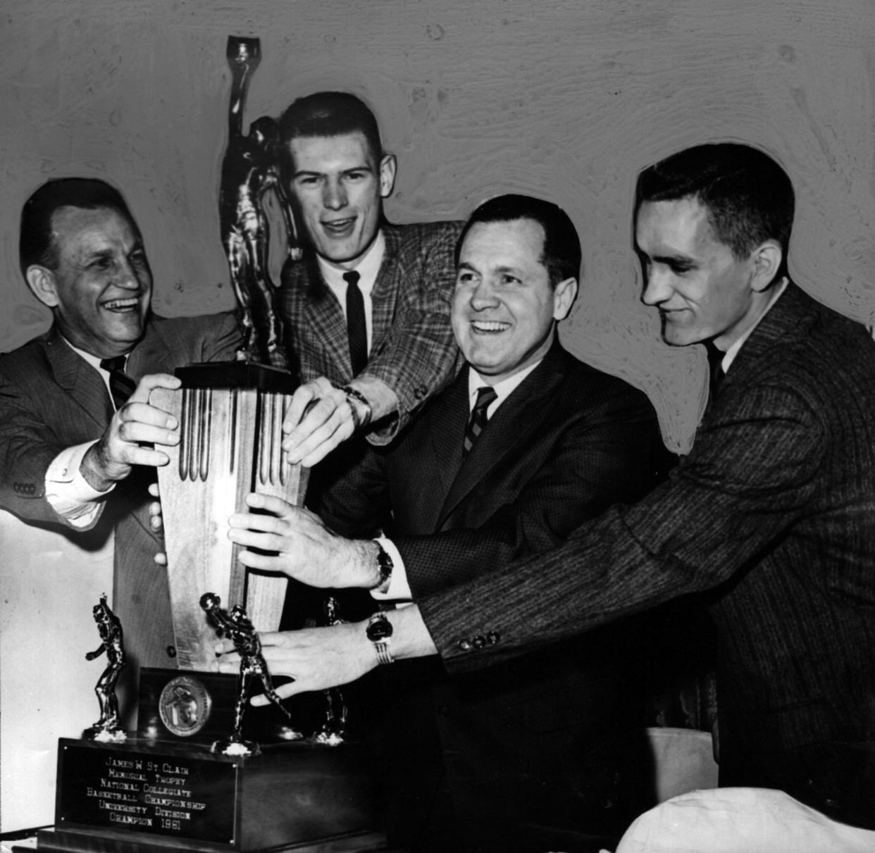 March 28, 1961: "The Big One" - That's what they're calling this trophy, symbolical of the National Collegiate Basketball Championship, yesterday at the UC Boosters Club meeting. Clasping it with happy hands are athletic director George Smith, center Dale Heidotting, coach Ed Jucker and cocaptain Carl Bouldin. Cincinnati Enquirer/Herb Heise