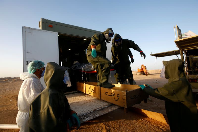 FILE PHOTO: Members of the Popular Mobilization Forces (PMF) bury people who passed away due to coronavirus disease (COVID-19) at the new Wadi Al-Salam cemetery on the outskirts of the holy city of Najaf