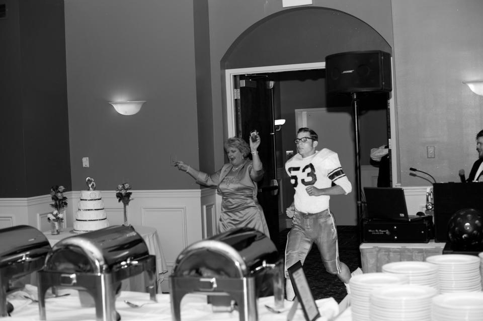 A photo of George Shoop from his high school football days was added to this photo of the mother of the groom making her entrance at the reception. To include George Shoop in the event, the mother of the groom held up a picture of her husband on her cellphone.