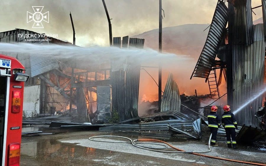 Firefighters work at a site of an industrial warehouse damaged by a Russian drone strike