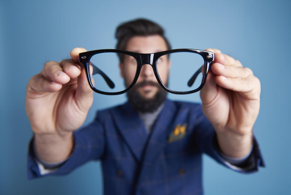 Man holding eyeglasses in front his face