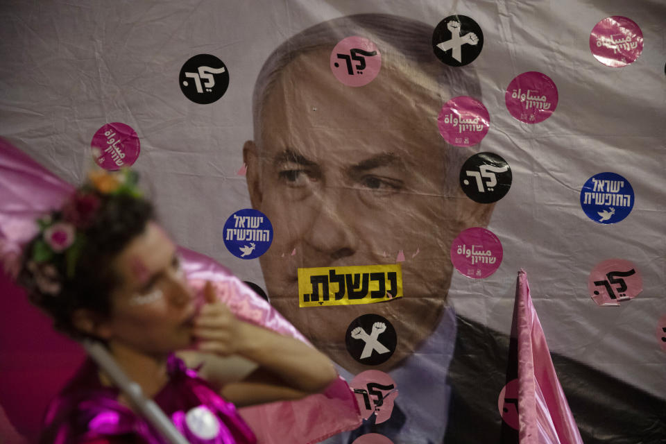 An Israeli protester wears pink during a demonstration against Israeli Prime Minister Benjamin Netanyahu outside his official residence in Jerusalem, Saturday, June 12, 2021. If all goes according to plan, Israel will swear in a new government on Sunday, ending Prime Minister Benjamin Netanyahu's record 12-year rule and a political crisis that inflicted four elections on the country in less than two years. Hebrew reads: "You failed"," Israel free" and "Leave". (AP Photo/Ariel Schalit)