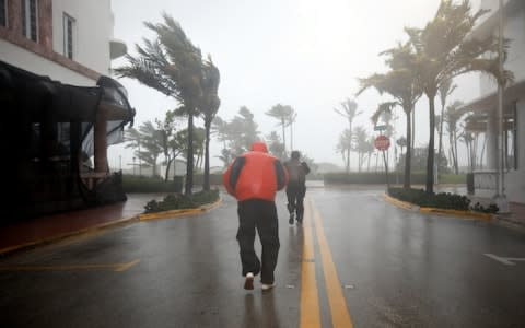 People walk along a street in South Beach as Hurricane Irma arrives at south Florida, in Miami Beach, Florida - Credit: CARLOS BARRIA