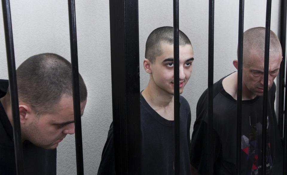 Two British citizens Aiden Aslin, left, and Shaun Pinner, right, and Moroccan Saaudun Brahim, center, sit behind bars in a courtroom in Donetsk, in the territory which is under the Government of the Donetsk People's Republic control, eastern Ukraine, Thursday, June 9, 2022. The two British citizens and a Moroccan have been sentenced to death by pro-Moscow rebels in eastern Ukraine for fighting on Ukraine's side. The three men fought alongside Ukrainian troops and surrendered to Russian forces weeks ago. (AP Photo)