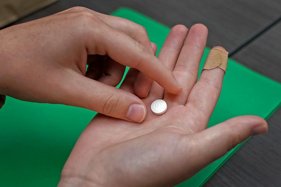 A patient prepares to take the first of two combination pills, mifepristone, for a medication abortion during a visit to a clinic in Kansas City, Kansas.