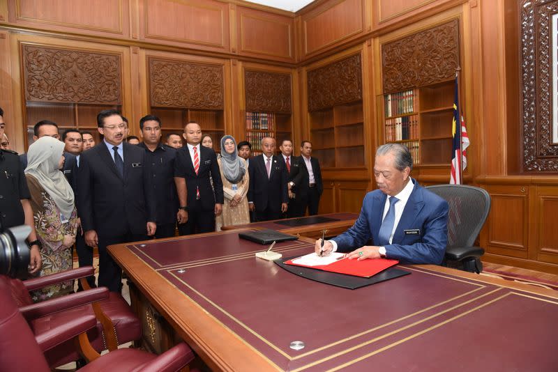 Malaysia’s Prime Minister Muhyiddin Yassin signs a document on his first day at the prime minister's office in Putrajaya