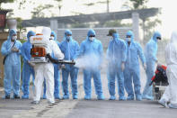 A health worker disinfects arriving Vietnamese COVID-19 patients at the national hospital of tropical diseases in Hanoi, Vietnam on Wednesday, July 29, 2020. The 129 patients who were working in Equatorial Guinea were brought home in a repatriation flight for treatment of the coronavirus. (Bui Cuong Quyet/VNA via AP)