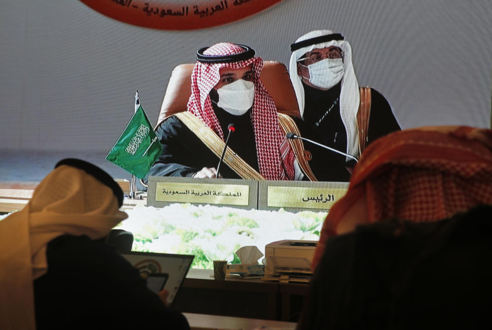 Journalists watch a large display screen in a press center, as Saudi Crown Prince Mohammed bin Salman, center left, chairs the 41st Gulf Cooperation Council (GCC) meeting, in Al Ula, Saudi Arabia, Tuesday, Jan. 5, 2021. Qatar's ruling emir arrived in Saudi Arabia to attend the high-level summit of Arab leaders, following an announcement that the kingdom would end its years long embargo on the tiny Gulf state. The Qatari emir's arrival in the kingdom's ancient desert city of Al-Ula on Tuesday was broadcast live on Saudi TV. (AP Photo/Amr Nabil)