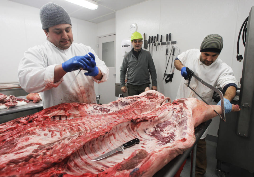 In this Tuesday, Jan. 22, 2013 photo, Robin Morris, center, watches Frank Pace, left, and Florin Ungureanu, butcher a pig in Waitsfield, Vt. Vermont officials are exploring a new round of value added agriculture, hoping their livestock industry might take advantage of the burgeoning world of charcuterie. “You can buy a pig for $3 a pound. You turn it into cuts and you'll get $4, $5, $6 a pound. Turn it into bacon and you're getting $8 maybe $9 a pound. Turn it into cured products, the world's your oyster,” said Robin Morris, founder of the Mad River Food Hub, an incubator for new food businesses that is adding rooms for producers to dry cure meats such as salamis, prosciuttos and sopressatas. (AP Photo/Toby Talbot)