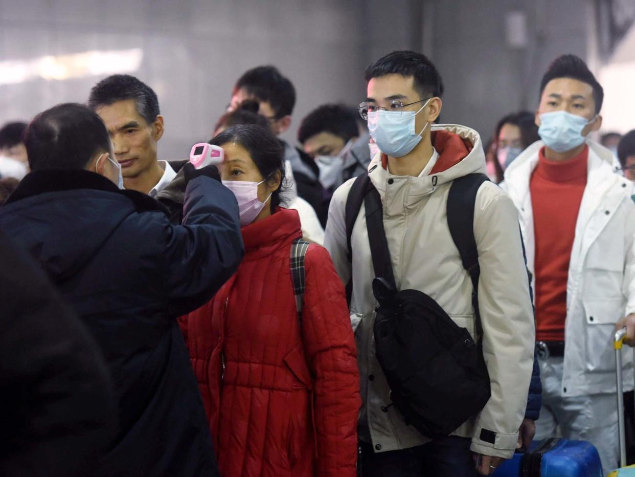 Workers use infrared thermometers to check the temperature of passengers arriving from Wuhan at a train station in Hangzhou in eastern China's Zhejiang Province: Chinatopix via AP