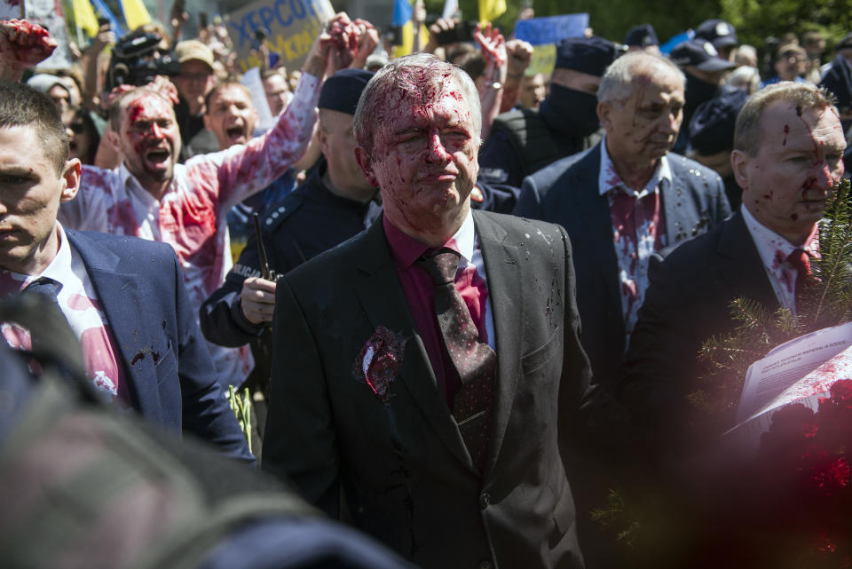 WARSAW, MAZOWIECKIE, POLAND - 2022/05/09: Russia's ambassador to Poland, Sergey Andreev (in the middle) covered in red paint leaves the Soviet soldiers cemetery. Hundreds of Ukrainians and Polish activists protested at a Warsaw cemetery to Red Army soldiers who died during World War II. Russia's ambassador to Poland, Sergey Andreev, was hit with red paint by protesters opposed to the war in Ukraine at an annual Victory Day event commemorating the end of World War II. Ambassador Sergey Andreev arrived at the Soviet soldiers cemetery to lay flowers on Victory Day, but the diplomat and his delegation were forced to leave the area, accompanied by police officers. (Photo by Attila Husejnow/SOPA Images/LightRocket via Getty Images)