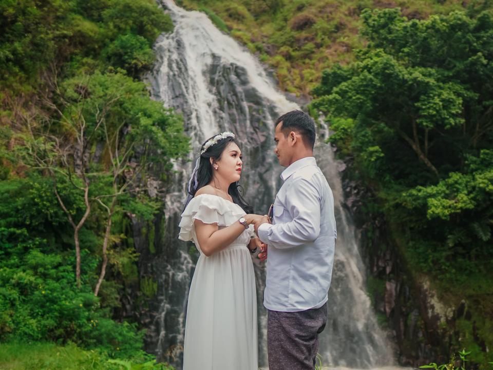 A couple taking wedding photos in front of a waterfall