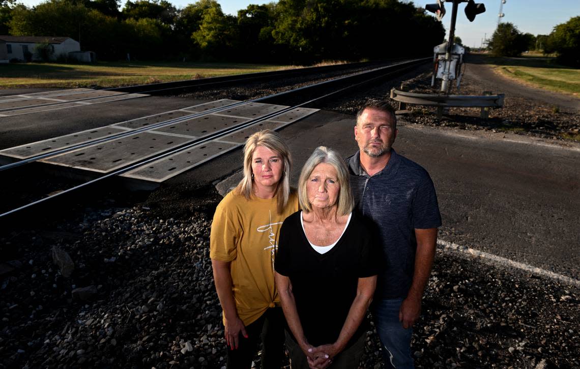 Gene Byrd’s widow Linda, center, and their children, Shantel McDonald and Chad Byrd, stand at the Maple Street crossing in Noble, Oklahoma, where an idling train blocked rescue crews trying to get to Gene Byrd’s home after he suffered a heart attack.