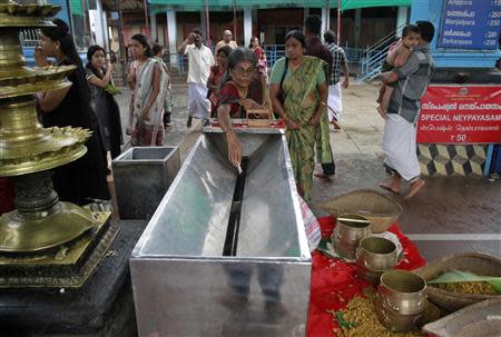 A devotee puts a ten rupee note into the Bhandaram or a donation box at the Chottanikkara Bhagavathy temple run by Cochin Devaswom Board on the outskirts of the southern Indian city of Kochi September 21, 2013. REUTERS/Sivaram V