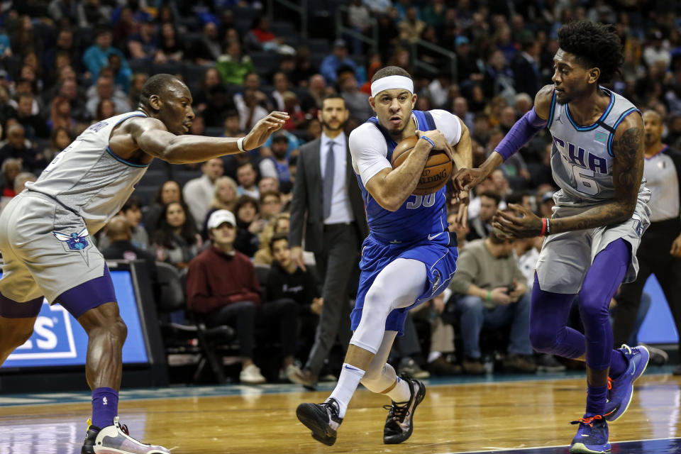 Dallas Mavericks guard Seth Curry, center, drives between Charlotte Hornets center Bismack Biyombo, left, and Charlotte Hornets forward Jalen McDaniels during the second half of an NBA basketball game in Charlotte, N.C., Saturday, Feb. 8, 2020. Dallas won 116-100. (AP Photo/Nell Redmond)