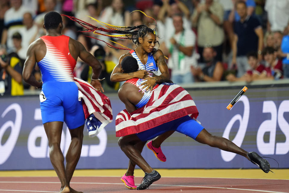 Sha'Carri Richardson, of the United States is greeted by members of the US men's team as she celebrates anchoring her team to gold in the Women's 4x100-meters relay final during the World Athletics Championships in Budapest, Hungary, Saturday, Aug. 26, 2023. (AP Photo/Petr David Josek)