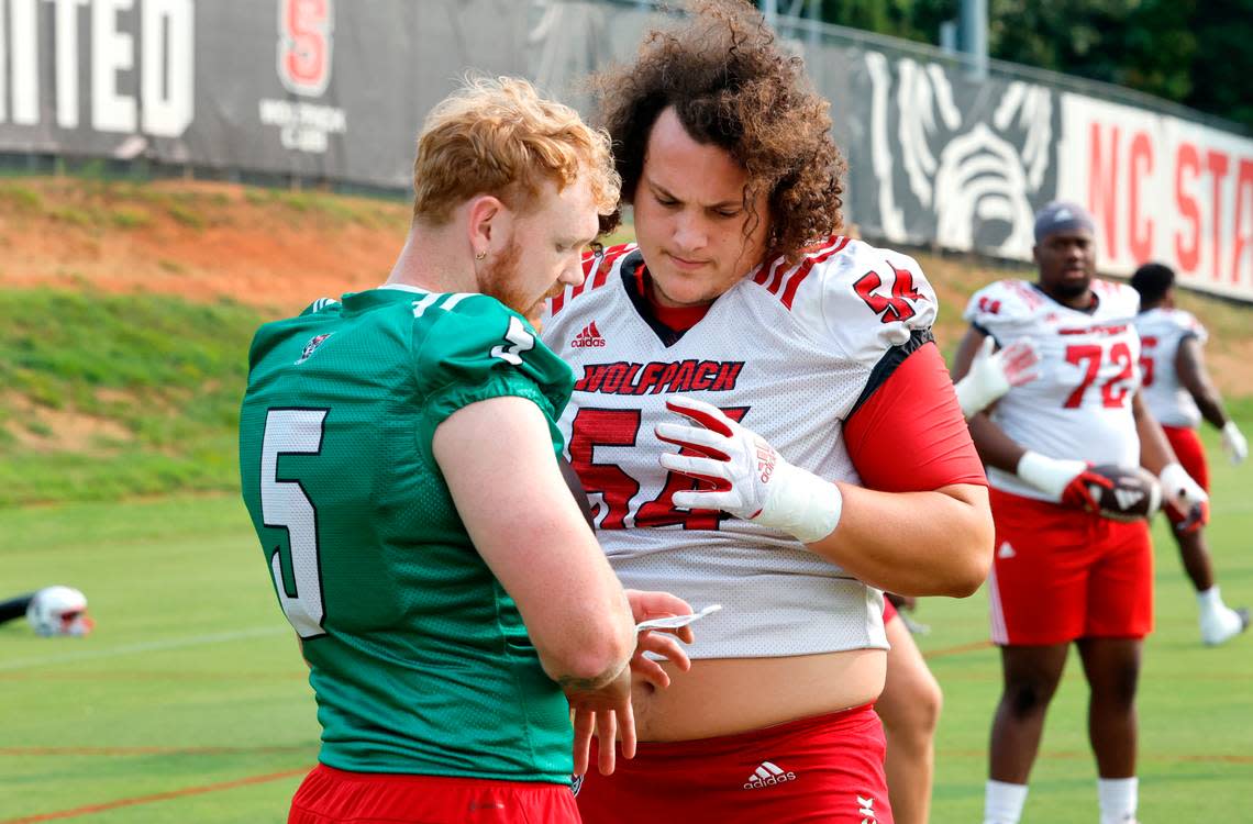 N.C. State quarterback Brennan Armstrong (5) talks with offensive lineman Dylan McMahon (54) during the Wolfpack’s first fall practice in Raleigh, N.C., Wednesday, August 2, 2023. Ethan Hyman/ehyman@newsobserver.com