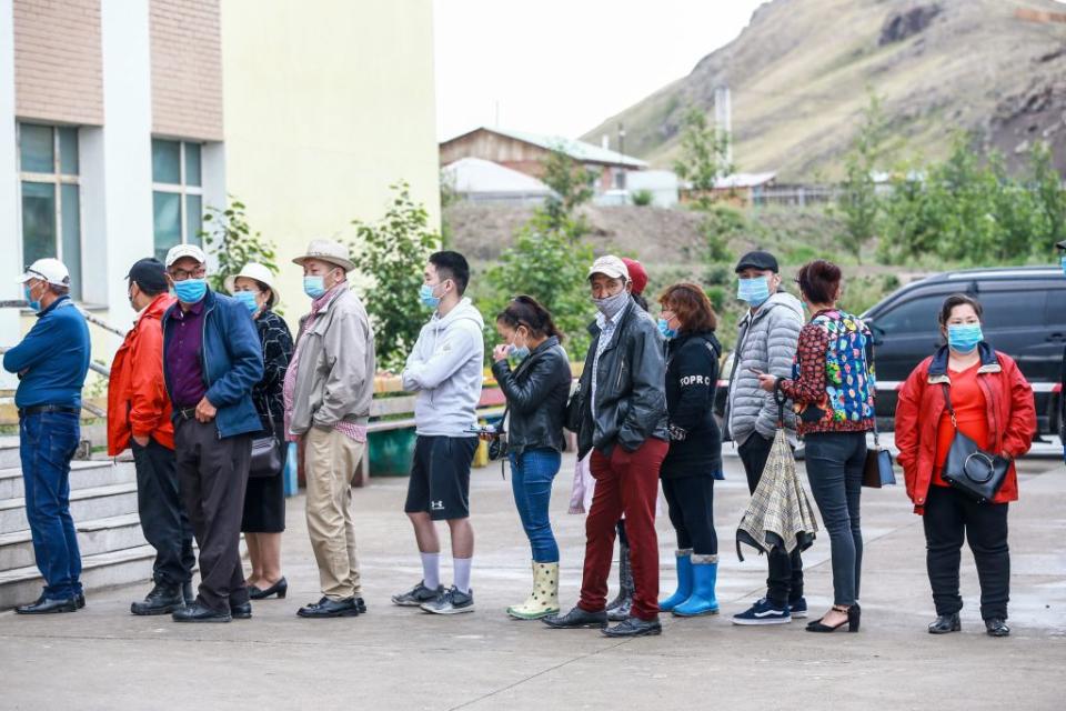 Mongolians seen queuing wearing face masks.